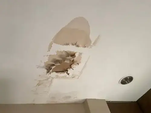 A ceiling opened where water-damaged drywall was cut out, water damage restoration in Brookline, MA
