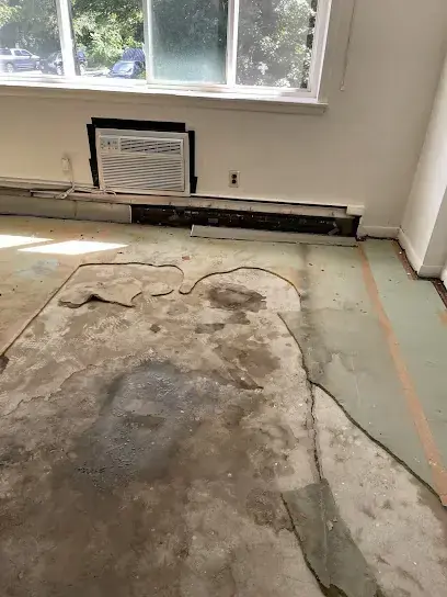 A room with the flooring pulled up to the bare subfloor so it can dry, water damage restoration in Brookline, MA
