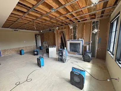 Air movers and a dehumidifier drying an opened room with the ceiling and flooring removed, structural drying in Brookline, MA